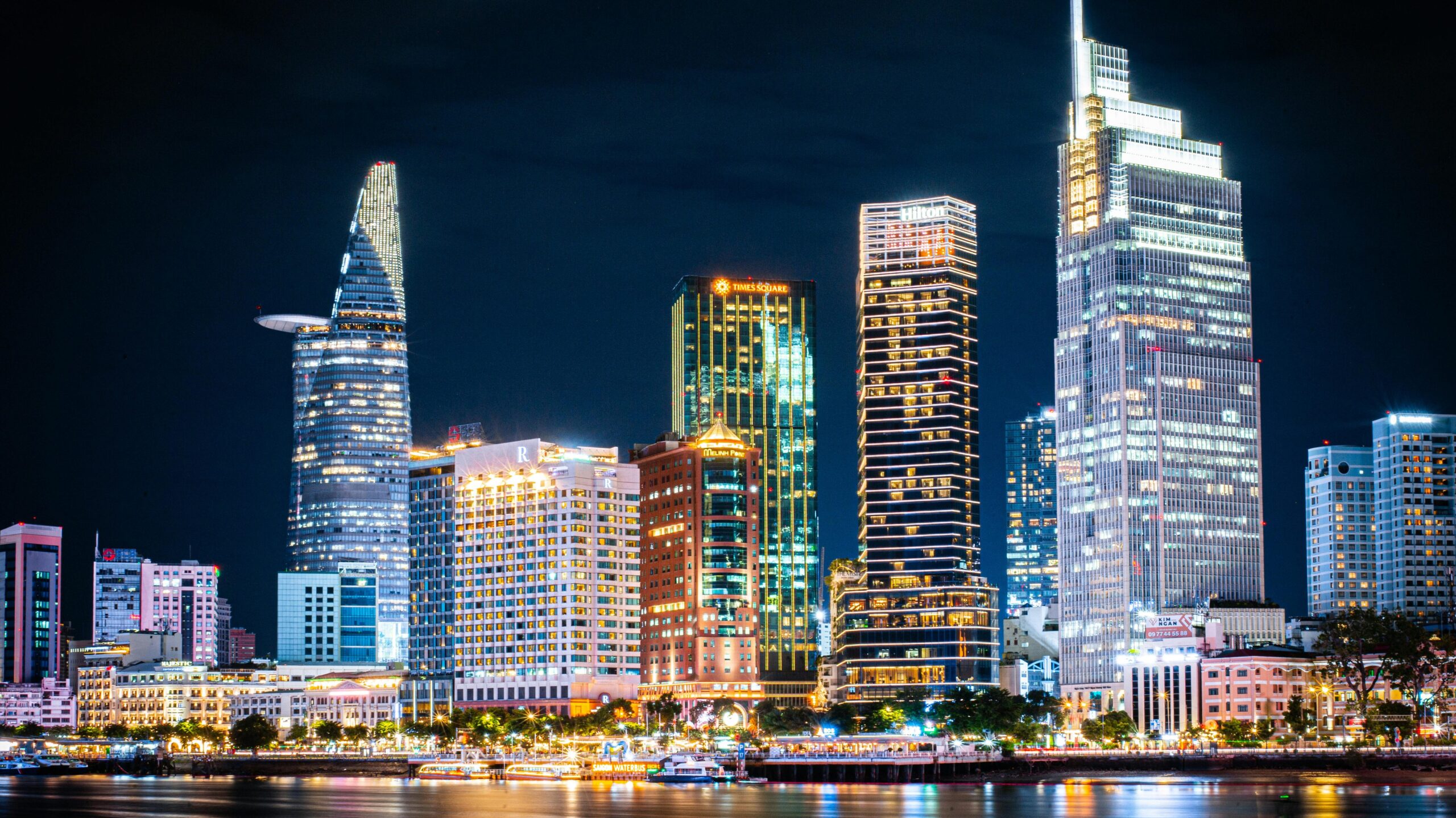 Stunning night view of Ho Chi Minh City's skyline with illuminated skyscrapers reflecting on the river.