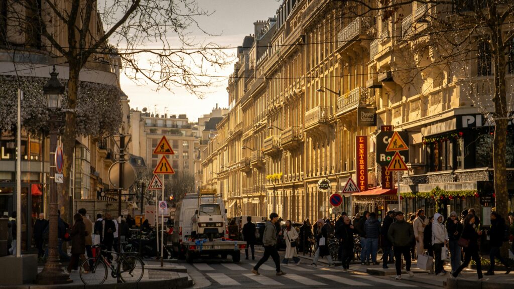 A bustling Parisian street scene with people and architecture in the warm winter sun.