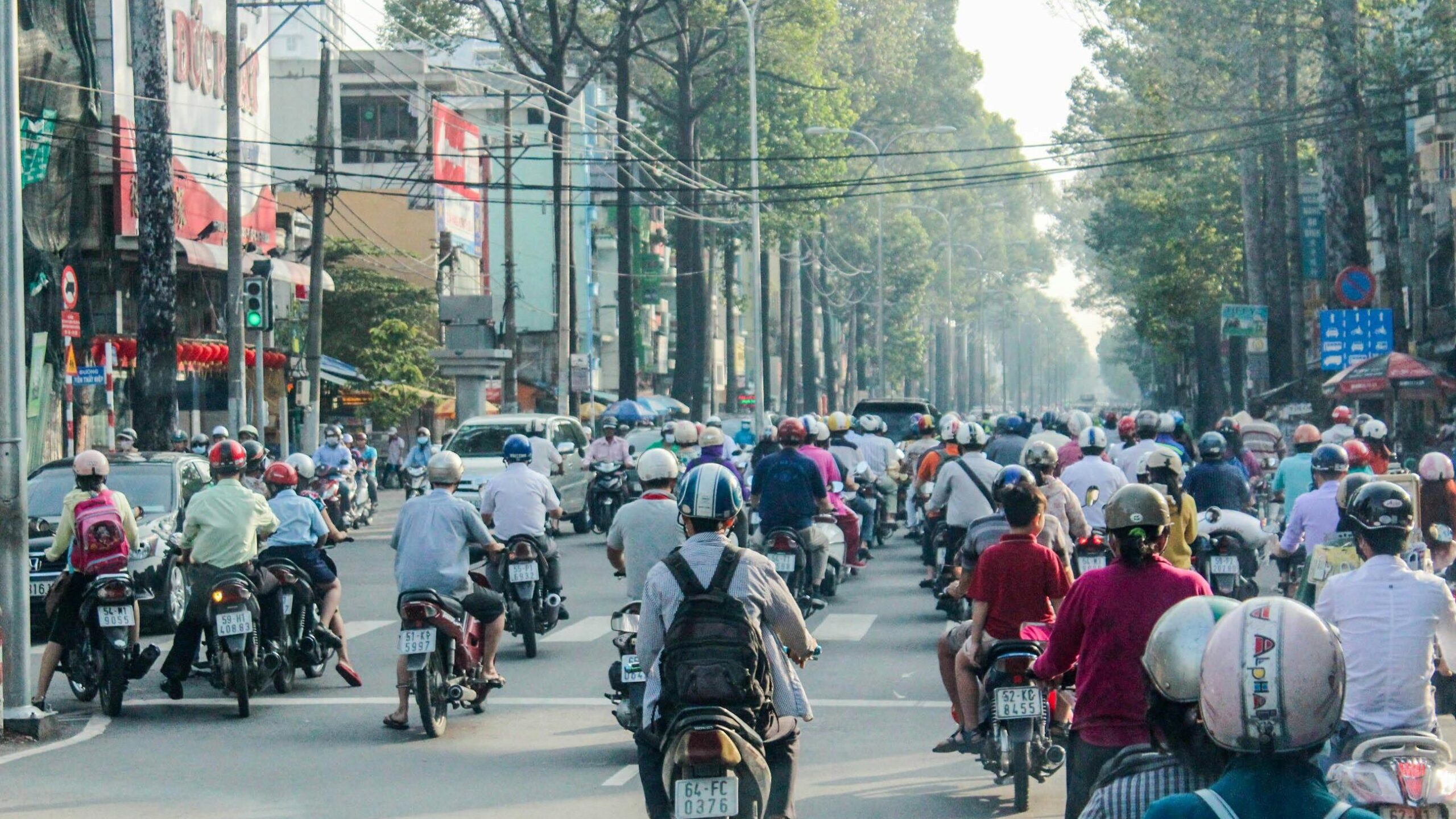 Motorbikes crowd a busy street in Ho Chi Minh City during daytime rush hour.