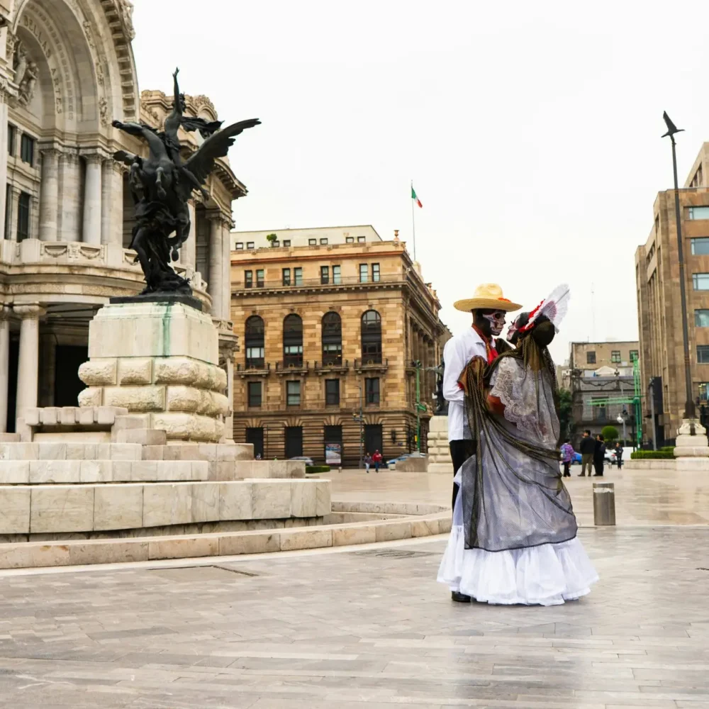 Couple in Catrina costumes dancing outside Palacio de Bellas Artes in Mexico City.